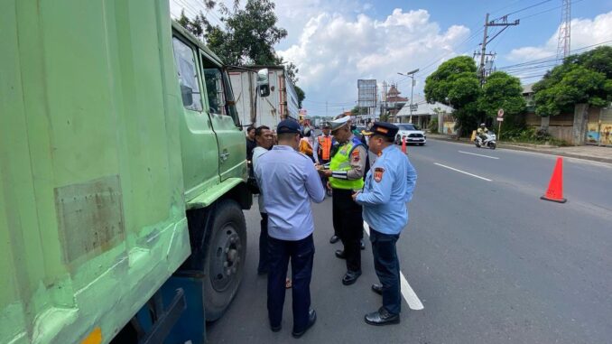 Petugas kepolisian sedang melakukan patroli pengawasan terhadap truk bermuatan berat.
