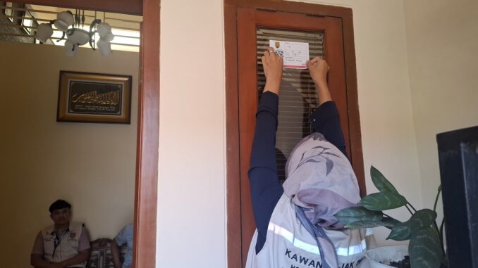 Petugas pajak Semarang memasang stiker IQRO pada bangunan sebagai bagian digitalisasi pajak daerah.